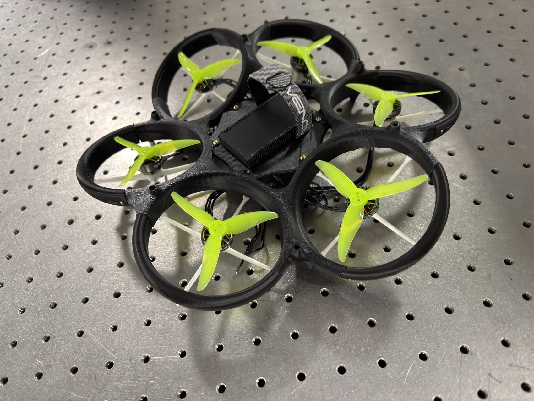 The fixed-tilt hexacopter with green flight props mounted, on an optical bench